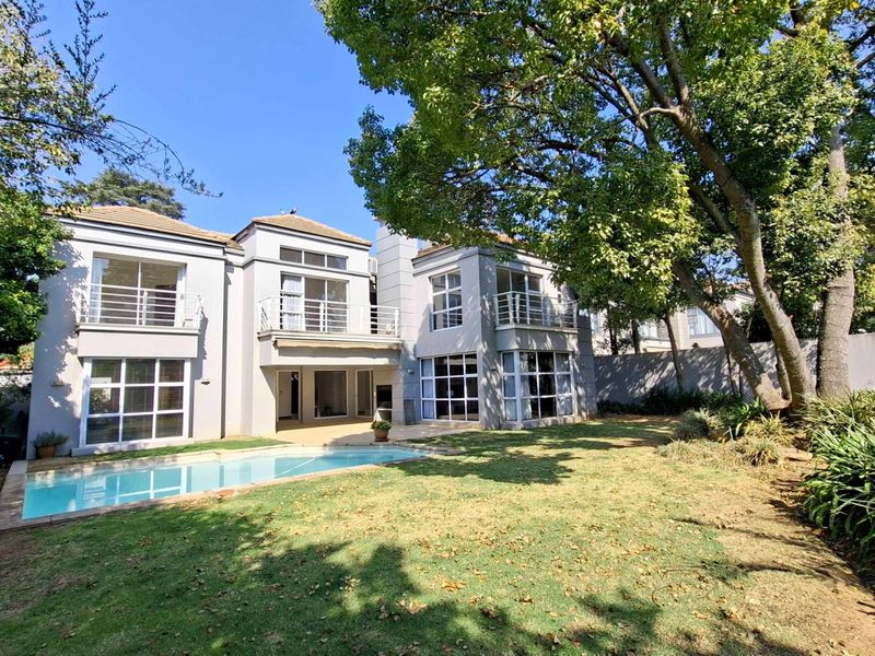 Rear view of a two-story townhouse featuring a swimming pool, landscaped garden, and multiple balconies with sliding glass doors.