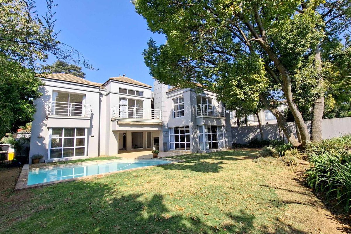 Rear view of a two-story townhouse featuring a swimming pool, landscaped garden, and multiple balconies with sliding glass doors.