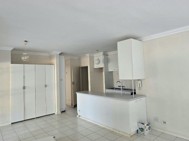 Open plan living area featuring a kitchen with built-in cabinetry, a breakfast bar, and tiled flooring throughout.