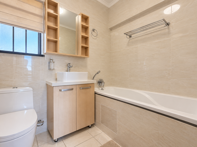 Modern bathroom featuring a vessel sink with vanity, bathtub with handheld shower, and neutral ceramic tiling throughout.
