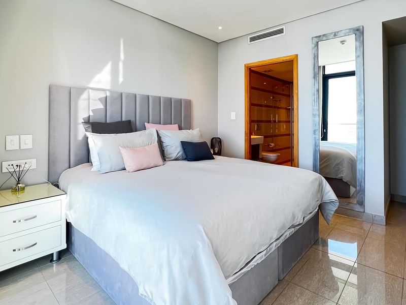 A modern, well-maintained bedroom featuring tiled flooring, recessed lighting, ducted air conditioning, and direct access to an en-suite bathroom.