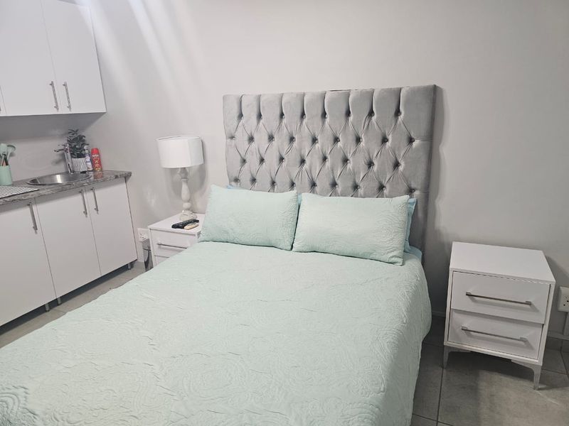 A bedroom featuring a kitchenette area with built-in cabinetry, a sink, and granite countertops, providing convenient utility within the sleeping space.