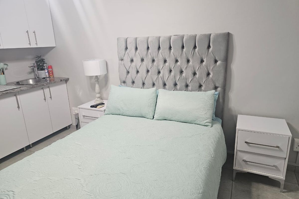 A bedroom featuring a kitchenette area with built-in cabinetry, a sink, and granite countertops, providing convenient utility within the sleeping space.