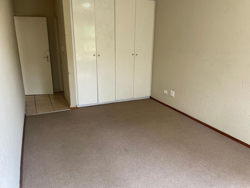 An empty bedroom featuring built-in cupboards, carpeted flooring, and neutral wall finishes, offering a blank canvas for potential updates.