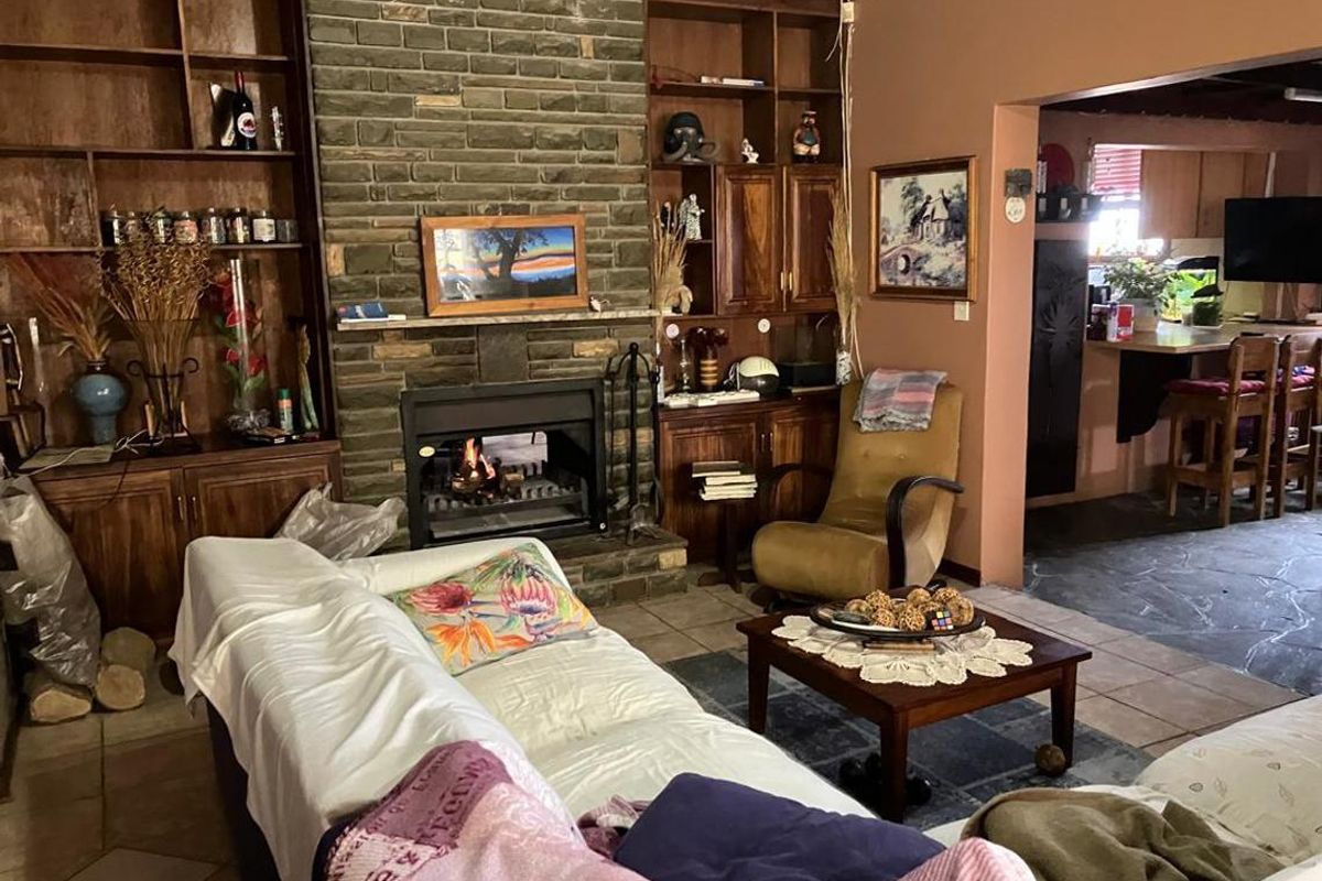 Cozy living room featuring a prominent stone fireplace with built-in wooden shelving and tiled flooring, offering a warm and traditional atmosphere.