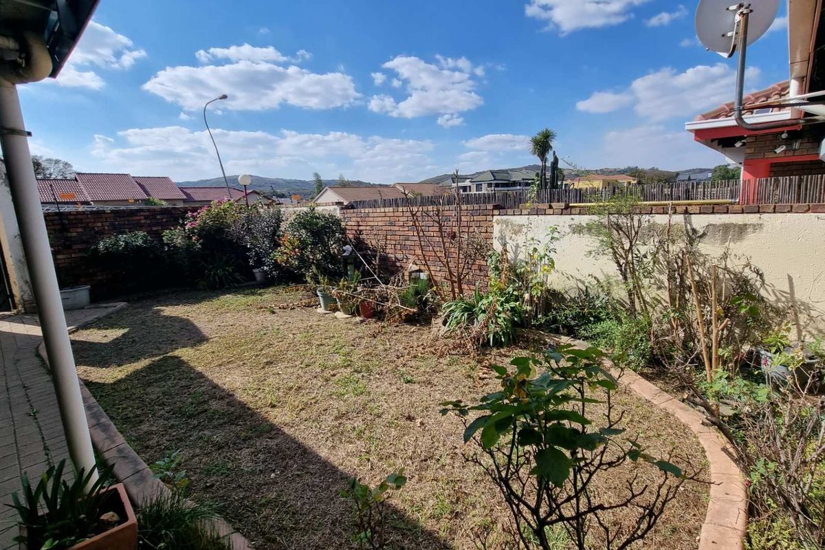 A private rear garden featuring a paved patio area, brick boundary walls, and established garden beds with lawn.