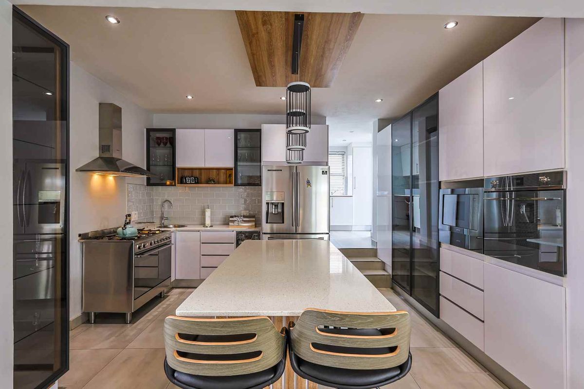 Modern kitchen featuring a central island with stone countertop, high-gloss cabinetry, stainless steel appliances, and integrated oven and microwave units.