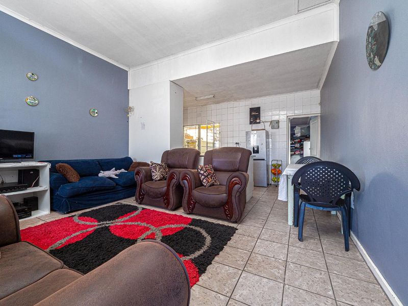 Open plan living and dining area featuring tiled flooring and a functional kitchen space with tiled splashbacks.