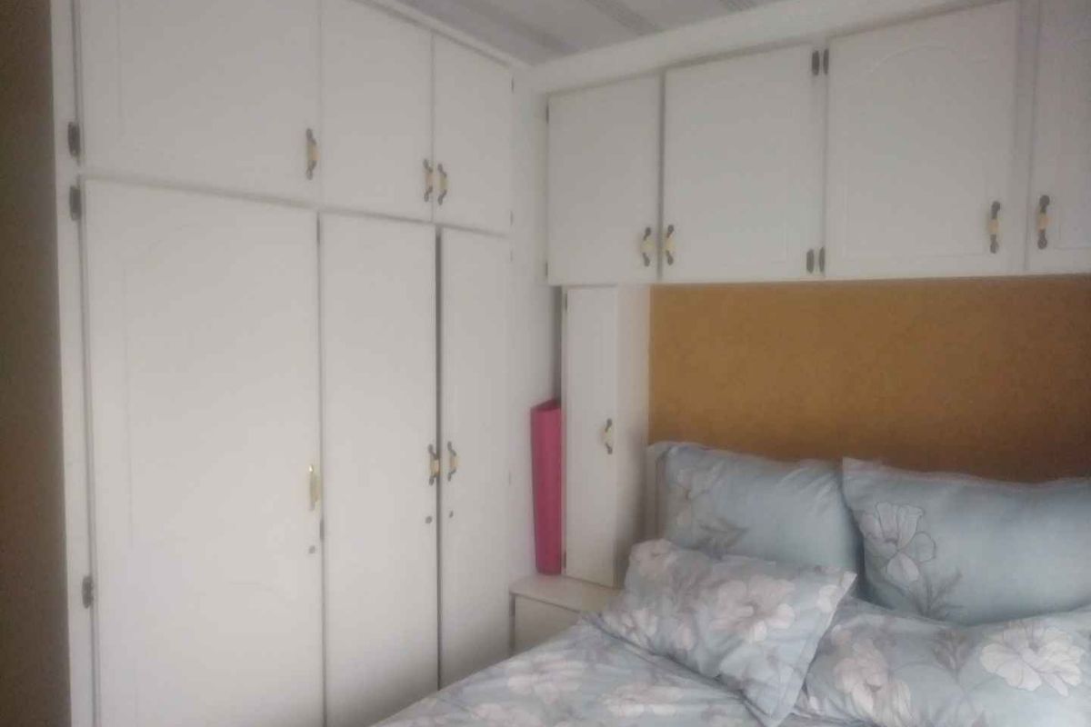 A bedroom featuring extensive white built-in cupboards and overhead storage units providing ample integrated storage space.