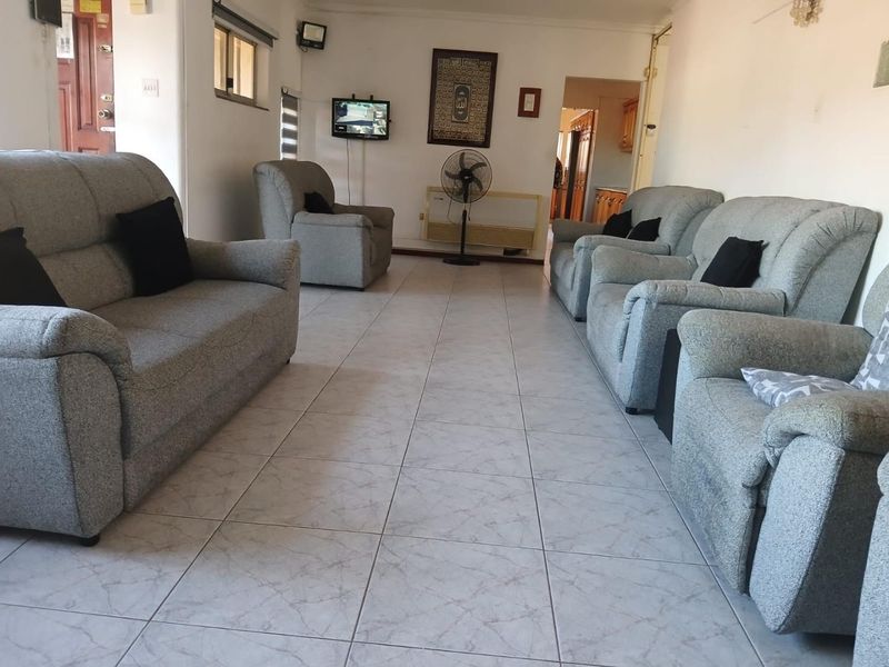A spacious living room featuring neutral tiled flooring and coving, providing a functional and well-lit area for relaxation.