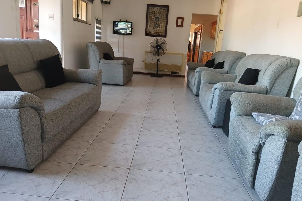 A spacious living room featuring neutral tiled flooring and coving, providing a functional and well-lit area for relaxation.