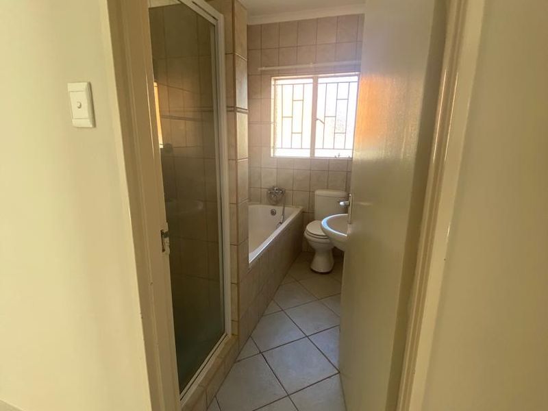 A functional bathroom featuring a shower enclosure, built-in bathtub, toilet, and pedestal basin with neutral tiled finishes.