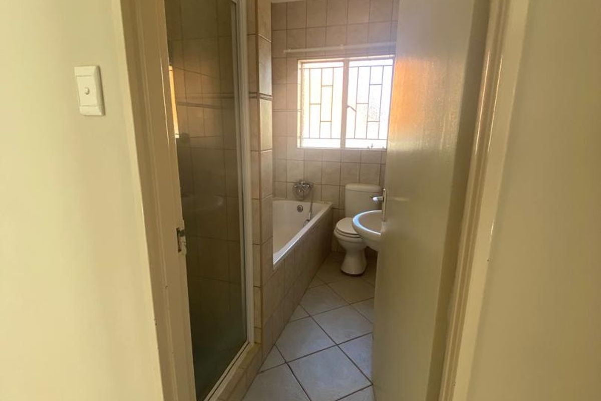 A functional bathroom featuring a shower enclosure, built-in bathtub, toilet, and pedestal basin with neutral tiled finishes.