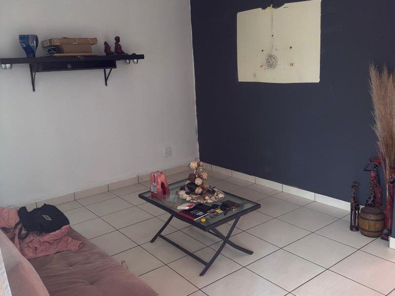 Living room featuring ceramic tiled flooring and a dark accent wall with visible electrical wiring and surface damage.