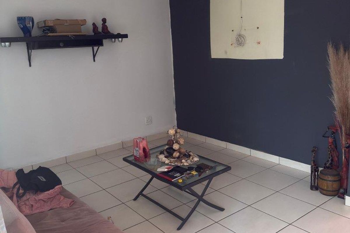 Living room featuring ceramic tiled flooring and a dark accent wall with visible electrical wiring and surface damage.