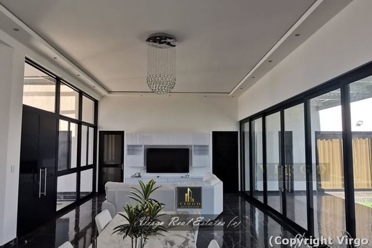 Modern living room featuring high ceilings, recessed lighting, a crystal chandelier, and expansive black-framed glass sliding doors opening to the outdoor area.
