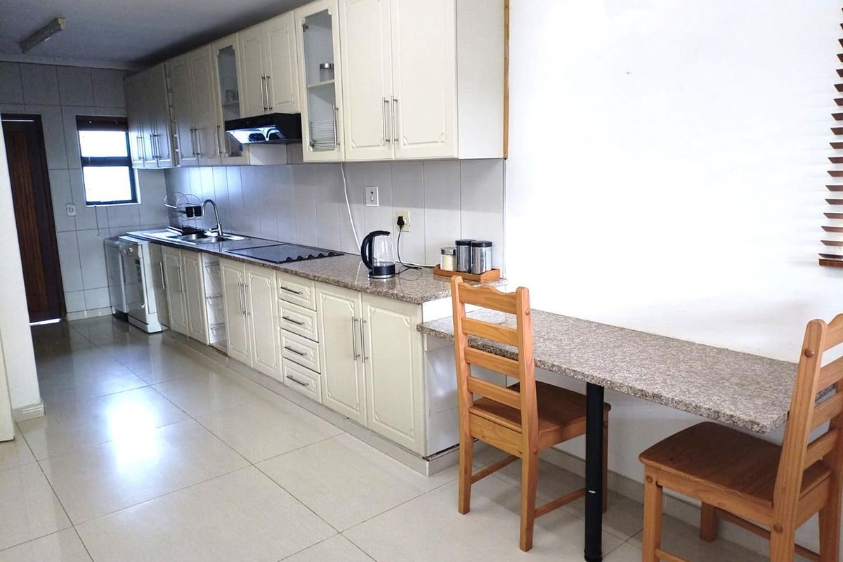 A functional kitchen featuring cream-colored cabinetry, granite countertops, a breakfast bar, and tiled flooring, offering a clean and practical workspace.