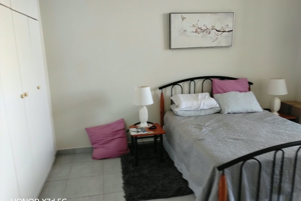 A functional bedroom featuring built-in wardrobes and tiled flooring, offering a clean and simple space ready for personalization.