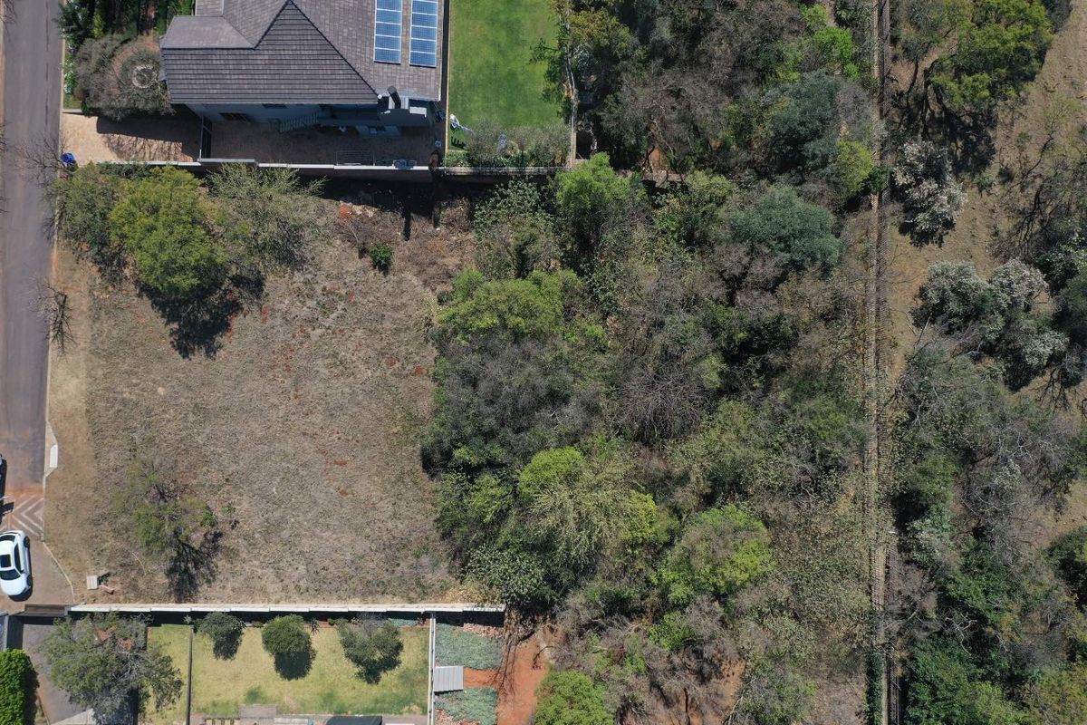 Aerial view of a vacant residential plot featuring established trees and boundary fencing, offering a clear perspective of the land's layout and surroundings.