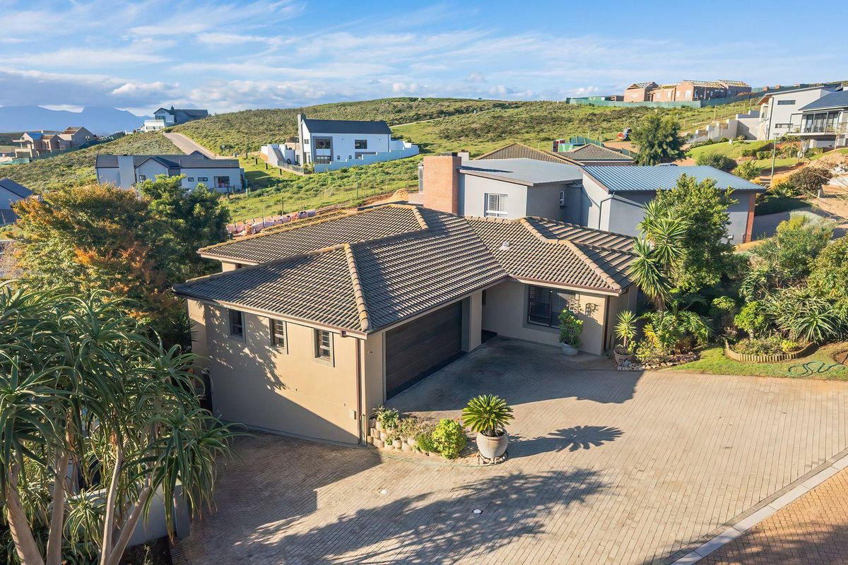 Aerial view of a modern residential property featuring a tiled roof, paved driveway, and double garage within a landscaped estate setting.