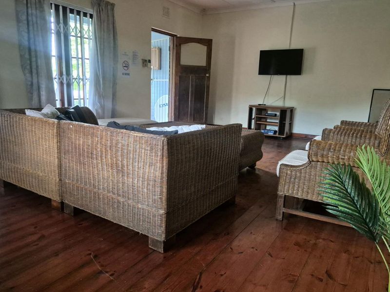 A living room featuring original timber flooring, a wooden door, and a window fitted with security bars.