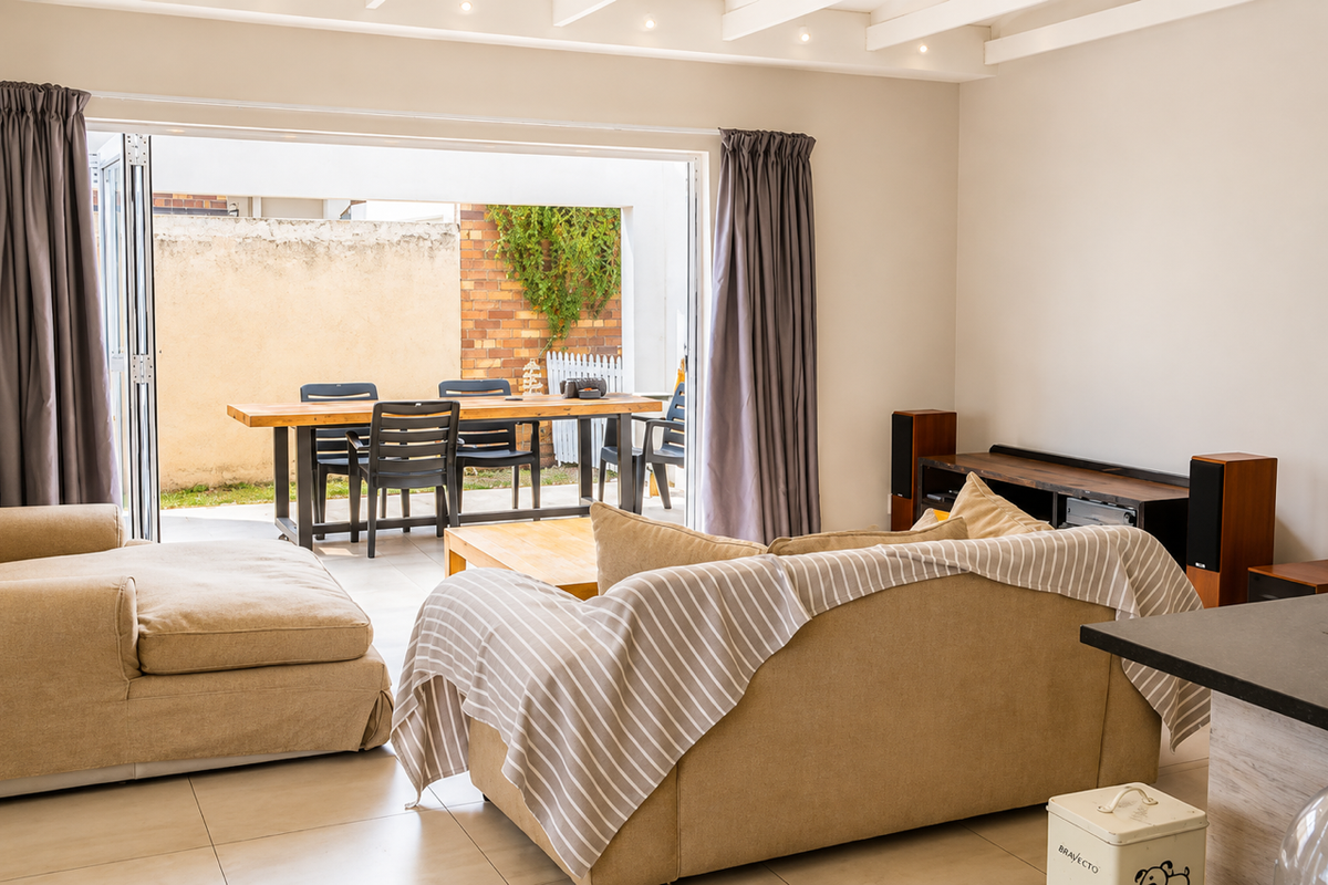 Bright living room featuring tiled flooring, exposed beam ceiling, and large bi-fold doors providing seamless access to the outdoor patio area.
