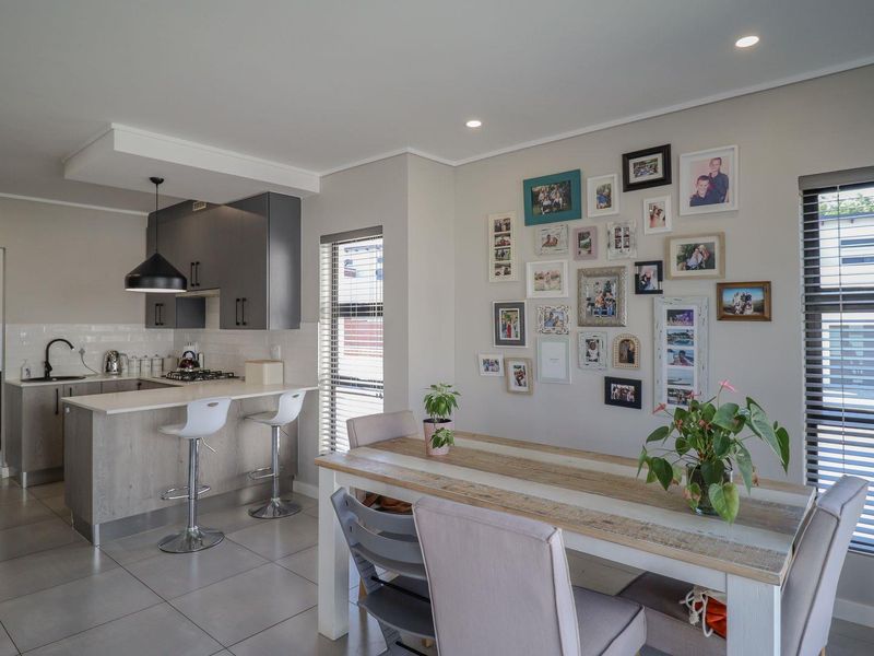 Modern open-plan kitchen and dining area featuring contemporary cabinetry, a functional kitchen island with gas hob, and neutral tiled flooring throughout.
