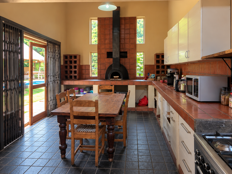 Spacious open-plan kitchen and dining area featuring a built-in pizza oven, tiled countertops, and direct access to the outdoor patio area.