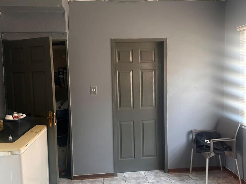 A functional laundry area featuring tiled flooring, a ceiling spotlight, and a built-in cupboard for storage.