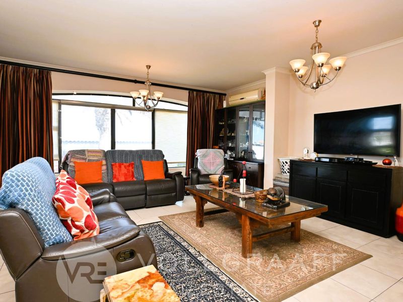 A comfortable living room featuring tiled flooring, a split-system air conditioner, and large sliding glass doors that provide natural light.