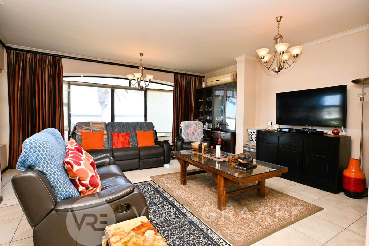 A comfortable living room featuring tiled flooring, a split-system air conditioner, and large sliding glass doors that provide natural light.