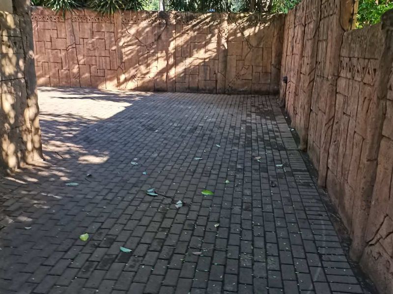 A private paved courtyard area enclosed by decorative textured boundary walls, offering a secluded outdoor space.