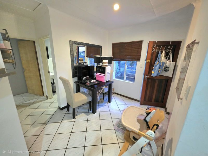 A small living area featuring tiled flooring, a timber entrance door, and venetian blinds, currently utilized as a multi-purpose space.