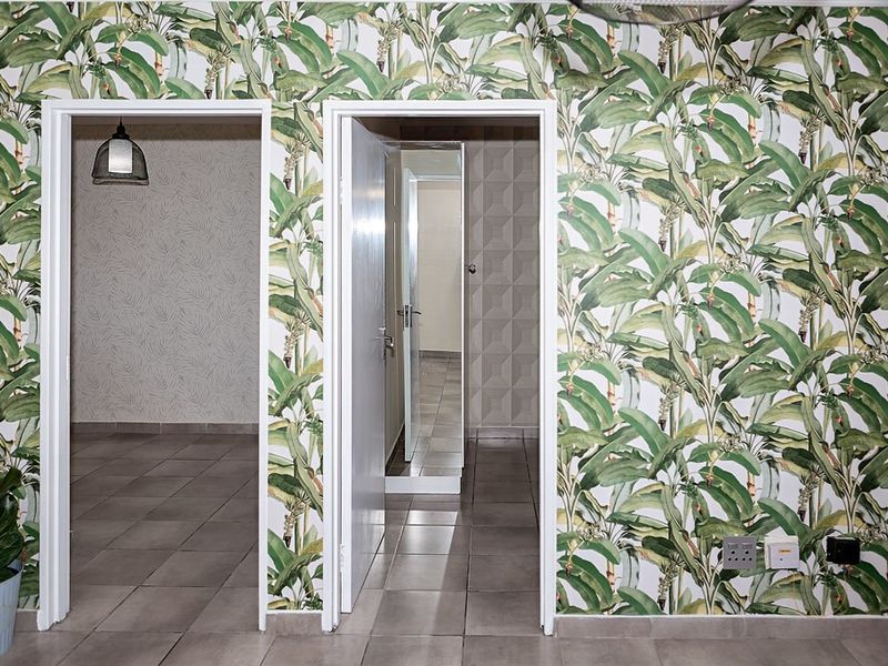 A bright hallway featuring patterned wallpaper, tiled flooring, and multiple doorways leading into adjacent rooms.