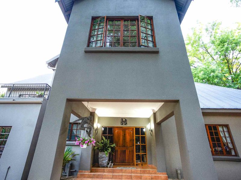 A well-maintained front entrance featuring a prominent two-story facade, solid timber front door, and classic timber-framed windows with tiled steps.
