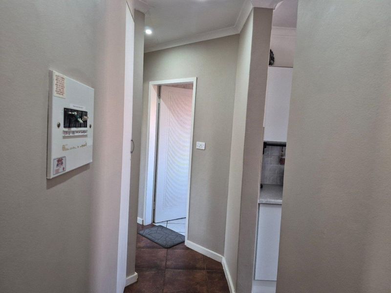 A functional hallway featuring tiled flooring, recessed downlighting, and a wall-mounted electrical distribution board, providing access to adjacent rooms.