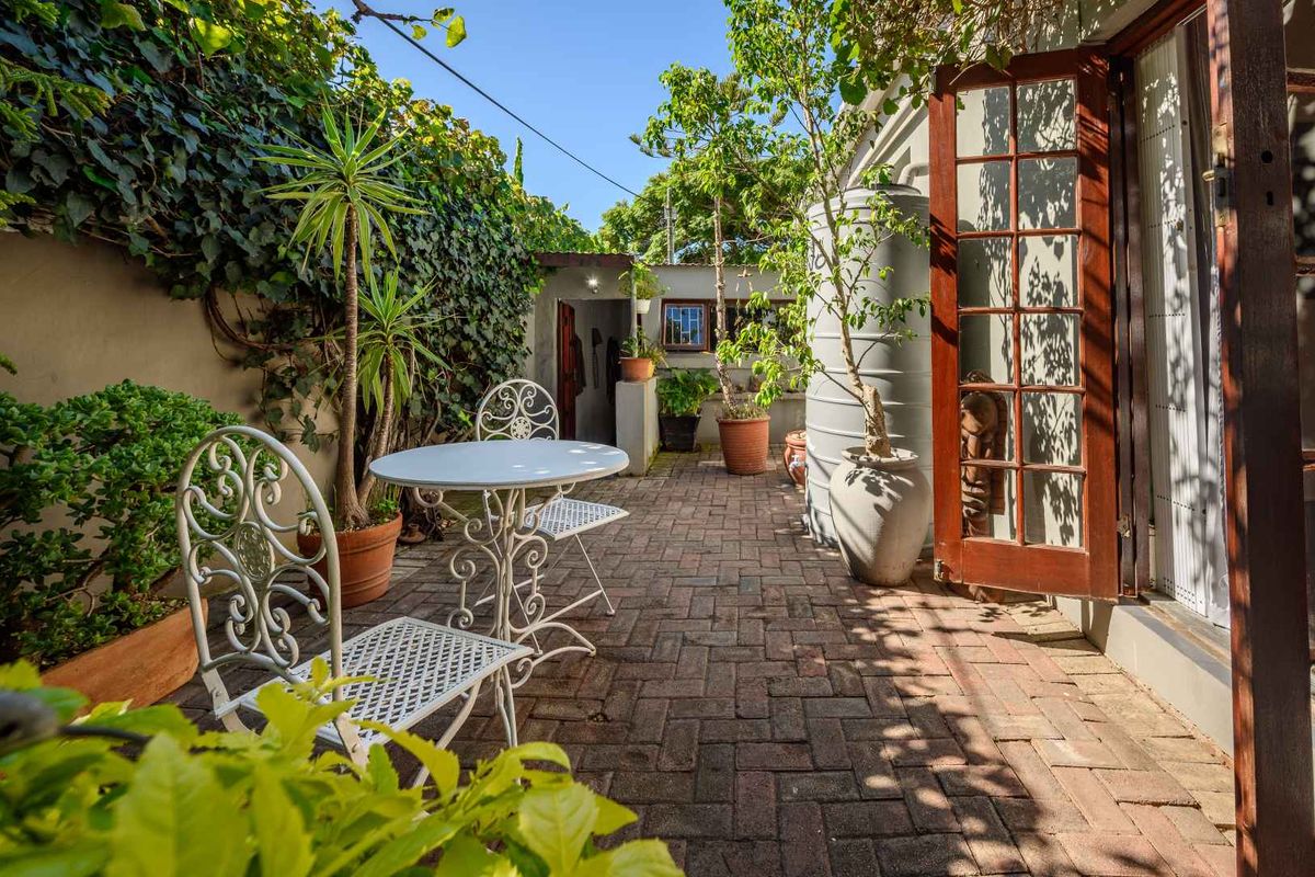 A private rear courtyard featuring brick paving, established climbing ivy on boundary walls, and direct access to the home via timber French doors.