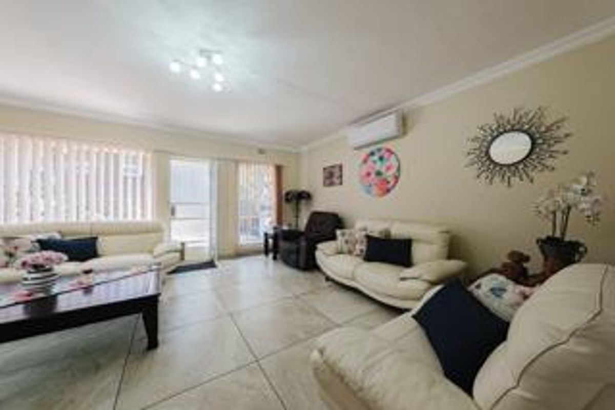 Spacious living room featuring large format floor tiles, a wall-mounted air conditioning unit, and sliding glass doors providing access to the exterior.