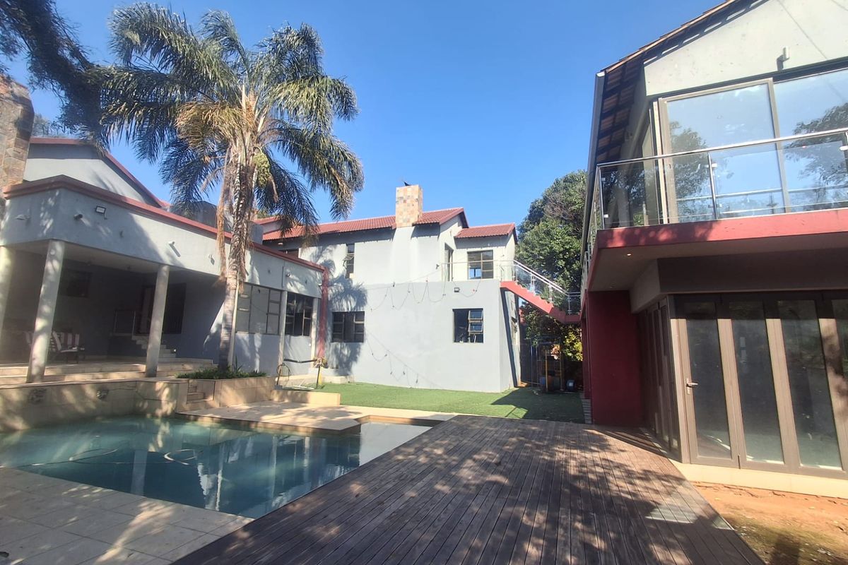 Spacious rear exterior featuring a swimming pool, timber decking, and a multi-level home structure with balconies and glass balustrades.