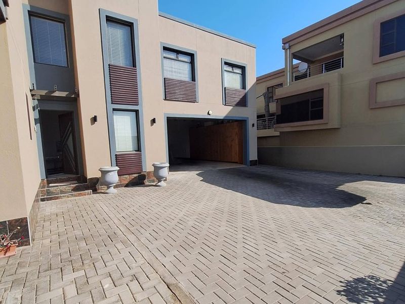 Front exterior view of a modern residential property featuring a paved driveway and integrated covered carport area.