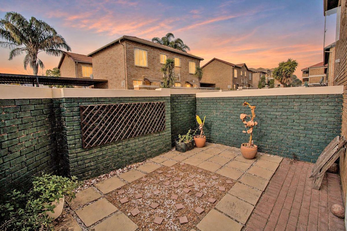 A private rear courtyard featuring a paved patio area enclosed by painted brick boundary walls, offering a quiet outdoor space.