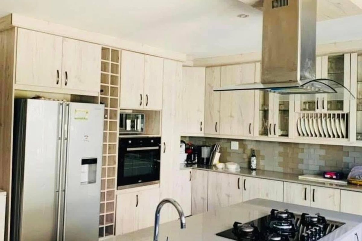 Modern kitchen featuring light wood cabinetry, a central island with a built-in gas hob, stainless steel extractor fan, and integrated oven.