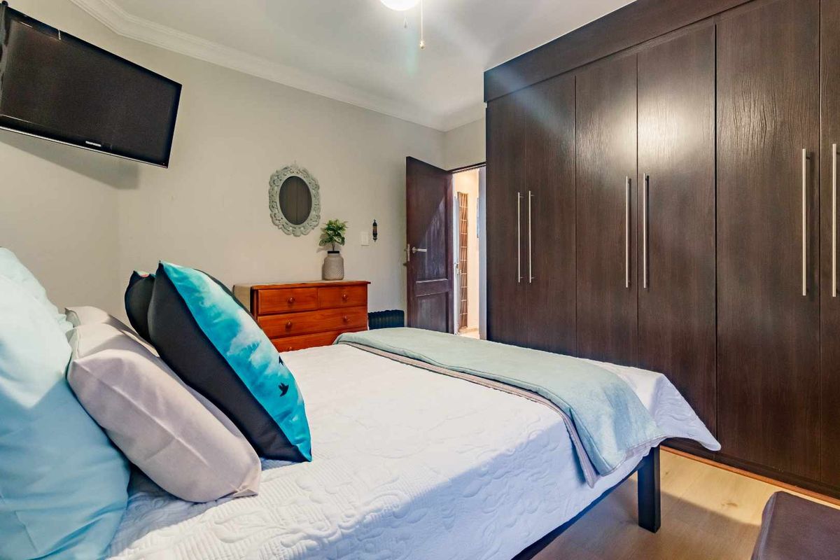 A well-maintained bedroom featuring dark wood built-in cupboards, laminate flooring, and crown molding.