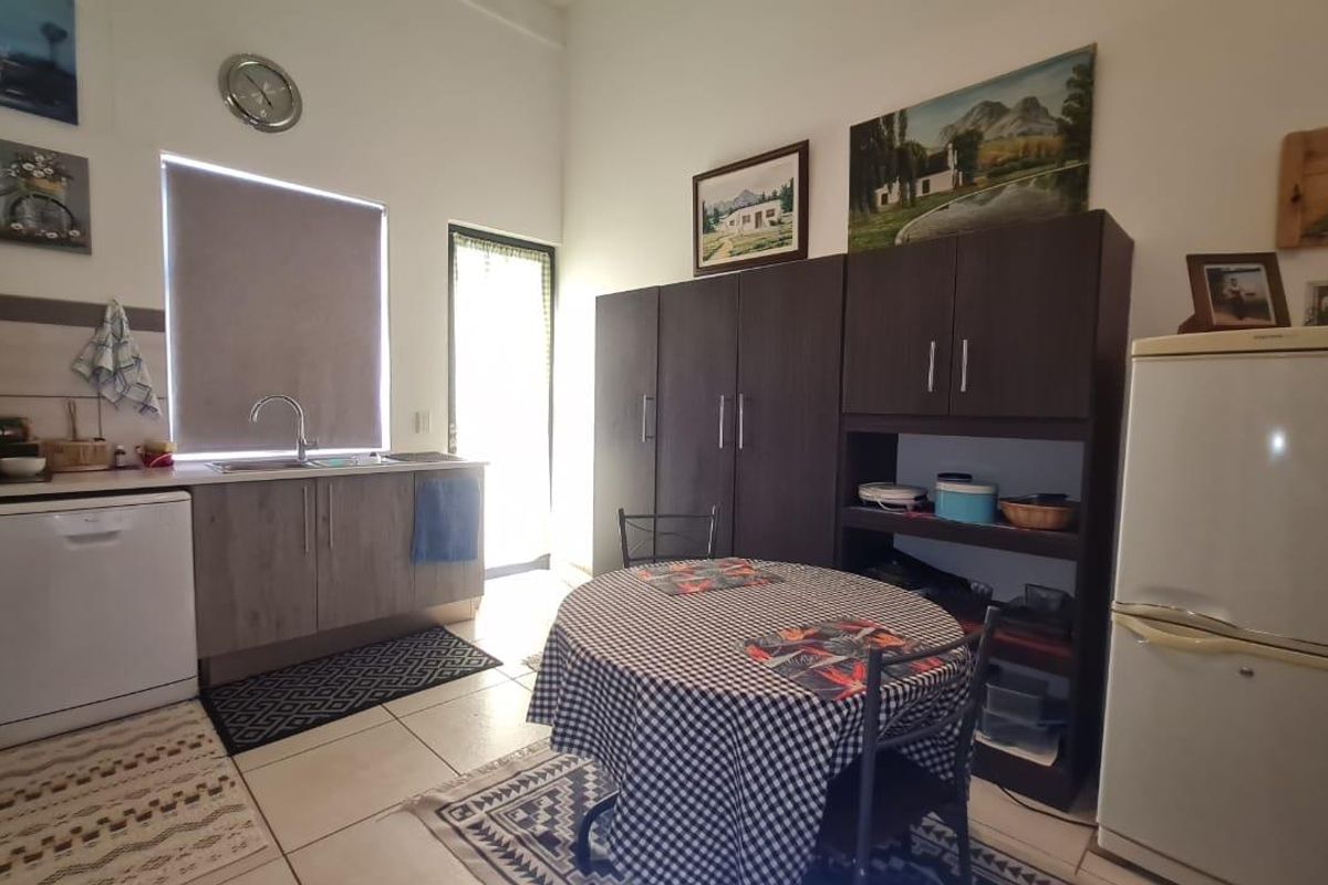 A functional kitchen area featuring built-in cabinetry, a stainless steel sink, and tiled flooring with direct access to an outdoor area.