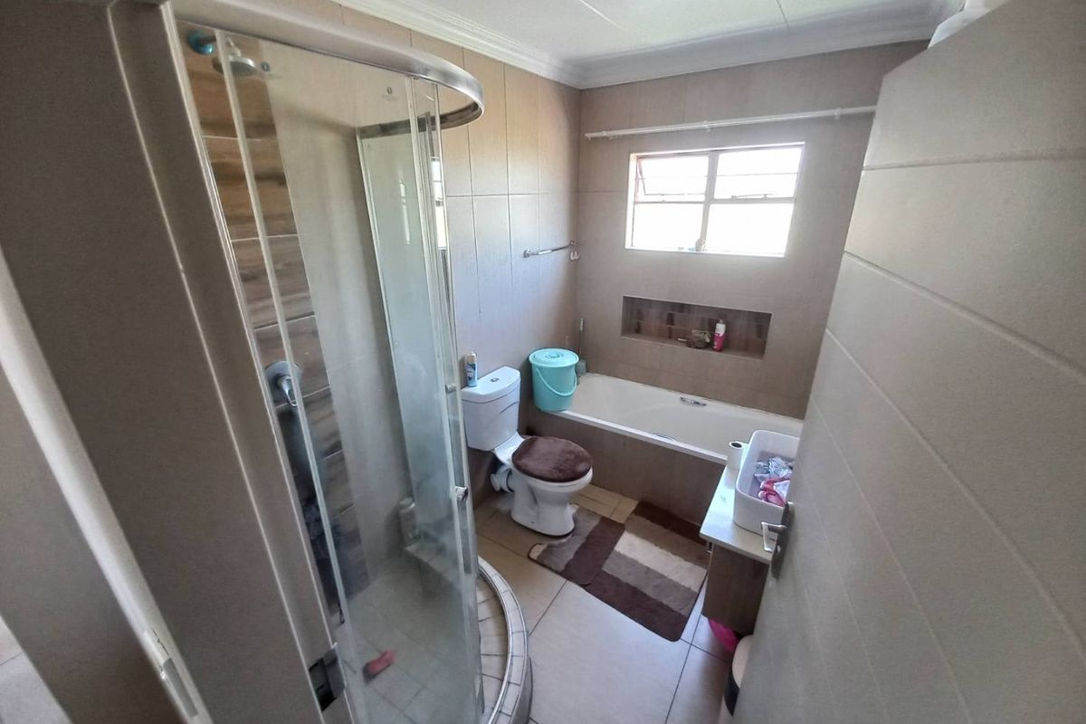 A functional bathroom featuring a separate shower enclosure, a built-in bathtub, a toilet, and a vanity unit with tiled walls and flooring.