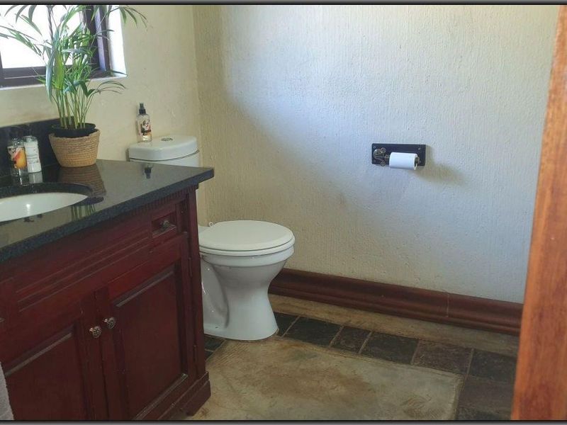 A functional bathroom featuring a dark wood vanity with a granite countertop, undermount sink, and standard toilet, with tiled flooring.