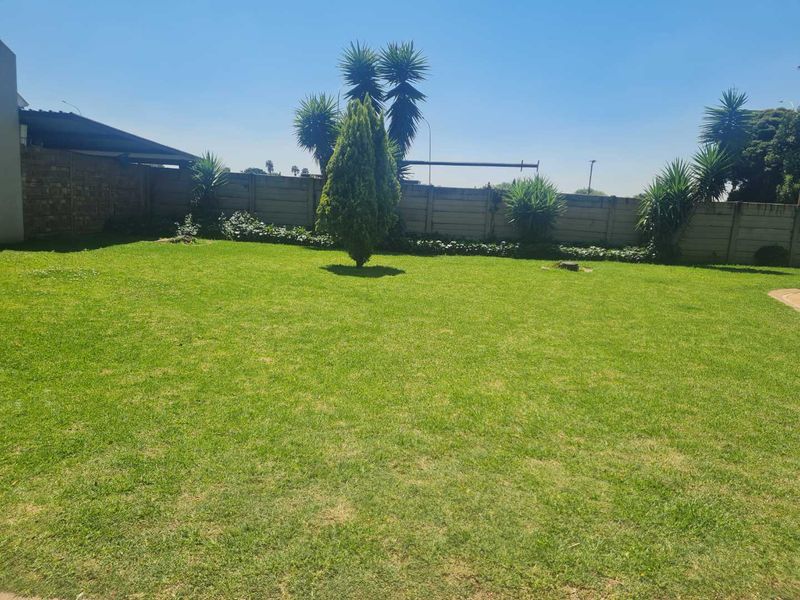 A spacious private garden featuring a well-maintained lawn and a secure precast concrete boundary wall.