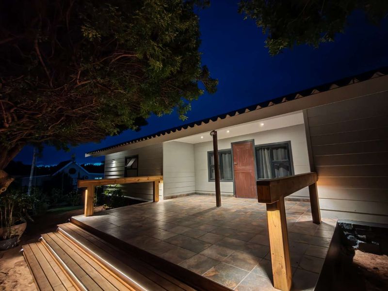 A well-lit, covered patio area featuring tiled flooring, timber handrails, and integrated step lighting, providing an inviting outdoor space.