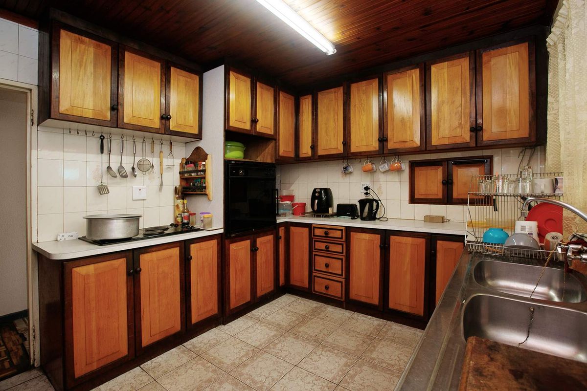 A functional kitchen featuring traditional timber cabinetry, tiled splashbacks, a built-in oven, and a double stainless steel sink.