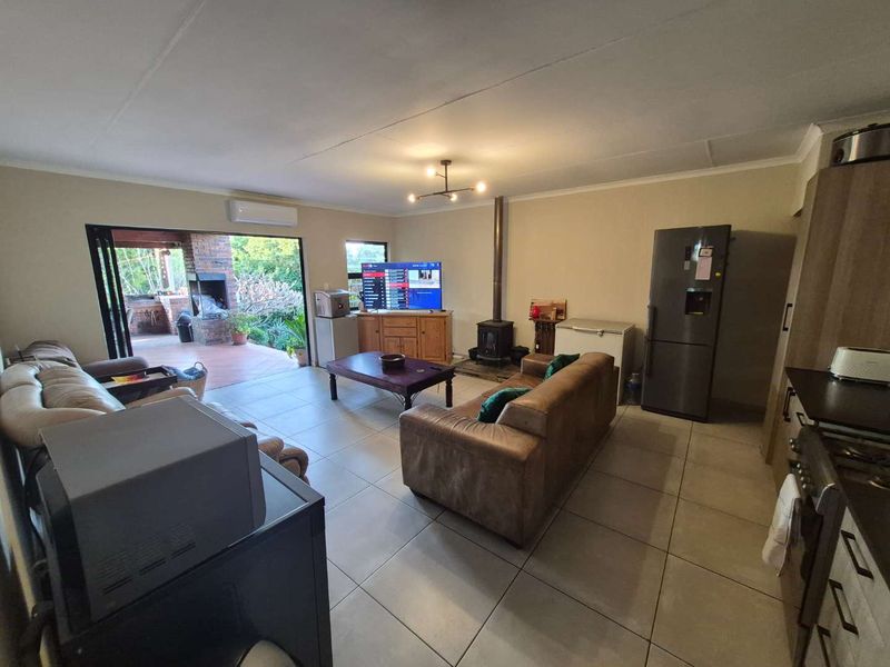 Spacious open-plan living area featuring tiled floors, a wood-burning fireplace, air conditioning, and seamless flow to an outdoor patio area.